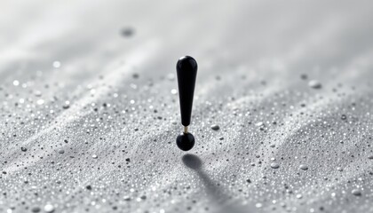 a black object with one end connected to a droplet like structure, positioned centrally against a dark background that appears to have a textured pattern