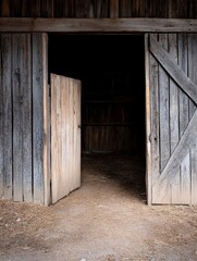 Aufkleber - Rustic wooden barn doors ajar, revealing a dark interior with hay strewn ground.  Sunlight illuminates the ground outside, creating a contrast between light and shadow. : Generative AI