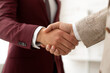 © Inspire Shots Hub - Close-up of two hands shaking, showcasing maroon and beige suit fabric textures. Represents agreement, partnership, and collaboration in business