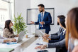 © Dusan Petkovic - Young leader standing at meeting room with his team around conference table of experts and having speech.