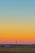 © cabedol - Sunrise over a vast, desolate plain. A small, simple building sits on the horizon.  Pale, blurred colors fill the sky