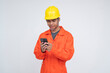 © Mdv Edwards - Young Southeast Asian male OFW in construction gear using smartphone to message or connect with relatives abroad during a break. Isolated on a light background.