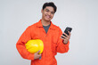© Mdv Edwards - Happy Southeast Asian construction worker smiling while holding a phone and helmet, representing successful money transfer via remittance app.