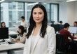 © Rehena - Asian businesswoman in white blazer stands in open office with colleagues