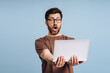 © Maria Vitkovska - Shocked man holding laptop showing astonishment and surprise