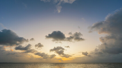 Fototapete - Sunset sky clouds over sea water background in evening with orange, blue sun light, Horizon sea ocean sunrise sky landscape nature backgrounds and gold sun down in golden hour summer season, Dusk sky