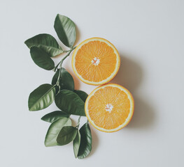 Aufkleber - Two juicy orange halves, segmented and vibrant, rest beside a lush sprig of green citrus leaves on a bright white background, creating a refreshing and healthy image. : Generative AI