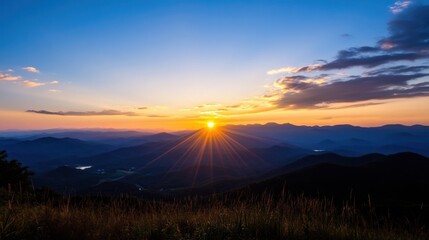 Poster - Majestic sunset over layered blue mountains, showcasing vibrant orange and yellow hues, with sun rays extending across the landscape. : Generative AI