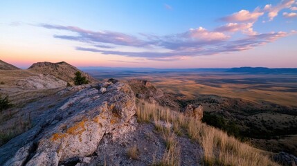 Poster - Sunset view from a rocky mountain peak overlooking a vast, golden prairie under a pastel sky.  The landscape stretches to the horizon, showcasing the beauty of the American West. : Generative AI