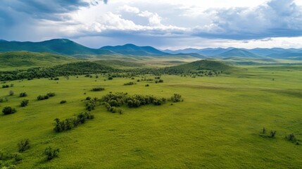 Poster - Vast green meadow stretches across a rolling landscape, under a partly cloudy sky, with distant blue mountains creating a serene, peaceful vista. : Generative AI