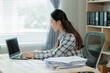 © Wanchai - Professional female accountant reviewing annual expense reports at her desk with a laptop and paperwork — ideal for finance, tax, and corporate business themes.