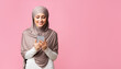 © Prostock-studio - Millennial muslim woman holding smartphone in hands, texting, reading message, or using new application, standing over pink background with free space