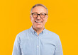 © Prostock-studio - Portrait of senior male smiling wearing glasses and casual checkered shirt posing standing isolated over yellow orange studio background. Happy excited adult person looking at camera, free copy space