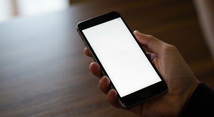 A hand holds a smartphone with a blank white screen, ideal for mockups and app designs.