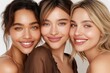 © vilaiporn - Three diverse women smiling together, showcasing friendship and beauty with natural makeup and glowing skin.