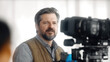 © visoot - Middle aged man, beard, casual vest, standing near professional video camera, indoor studio