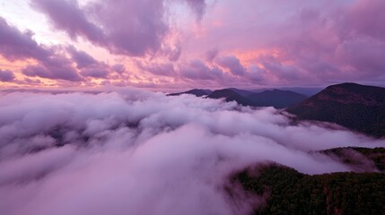 Aufkleber - Breathtaking pink-hued sunset casts a warm glow over misty mountain peaks and layered clouds, creating a serene and tranquil landscape at dusk