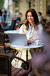 © sepy - Attractive woman witting at sidewalk cafe and using a notebook