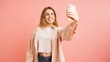 © DMegias - Young woman taking selfie with smartphone on pink background