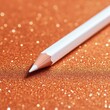 © อรุณ สตามัน - White pencil on sparkling orange surface with soft bokeh aesthetic creative stationery design
