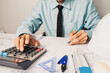 © PhotoJuthamat - Engineer calculating working mechanical strength with blueprints and construction plans for a building project, at his office desk