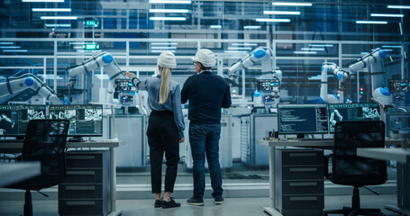 Fototapete - Diverse Factory Employees Using Laptop and Having a Conversation on a Production Floor. Robotic Arms Automate Electronics Assembly Inside a Facility. Automatic Conveyor is Powered by an AI Software
