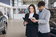 © anatoliycherkas - Car salesman showing contract details to businesswoman in a dealership
