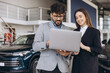 © anatoliycherkas - Car salesman showing laptop to customer in a dealership