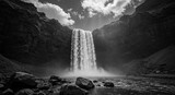 A waterfall is in the foreground of a black and white photo