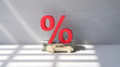 © Mirivox - Wooden car model on stack of money with red percentage sign, showcasing auto loan or car financing concept