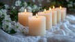 © Prokopchuk - Elegant still life featuring glowing wax candles surrounded by soft white flowers on a textured light fabric.