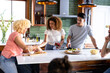 © wavebreak3 - Diverse friends preparing snacks together in modern kitchen, enjoying casual conversation