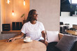 © BullRun - Young Black woman sitting in cozy café with cappuccino, smiling and enjoying peaceful moment, wearing casual clothes and radiating calmness and balance in warm stylish interior