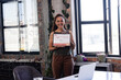 © Wavebreak Media - Mid adult woman standing in industrial style office loft, holding certificate and smiling