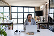 © Wavebreak Media - Diverse young adult woman working on laptop at industrial-style office, with headphones, coffee mug