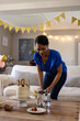 © Wavebreak Media - Woman leaning forward over coffee table in living room with cake, pitcher, banners and strawberries