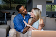 © WavebreakMediaMicro - African American man and woman sitting on couch, smiling and embracing at home