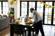 © wavebreak3 - Woman arranging cupcakes and snacks on dining table for festive celebration at home