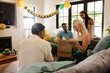 © wavebreak3 - Friends celebrating birthday at home, woman opening gift with excitement and joy