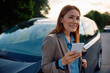 © Drazen - Happy businesswoman using app on mobile phone after driving car.