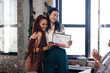 © WavebreakMediaMicro - Asian woman holding certificate hugging colleague in office, celebrating achievement