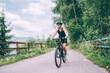 © Soloviova Liudmyla - Portrait of happy smiling woman dressed in cycling clothes, helmet and sunglasses riding bicycle on asphalt out-of-town bicycle path. Active sporty people concept image