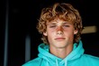 © kvladimirv - Portrait of a Young Man with Curly Hair in a Turquoise Hoodie Against a Dark Background