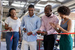 © wavebreak3 - Diverse team celebrating office opening, cutting ribbon and smiling together