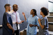 © WavebreakMediaMicro - Discussing patient care, African American medical professionals smiling in hospital hallway