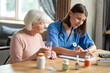 © zinkevych - Woman providing health care and assistance to aged patient offering treatment and medication