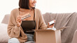 © Prostock-studio - Beauty Box Concept. Portrait of smiling asian lady received delivery package, holding eyeshadow palette for makeup, unpacking cardboard parcel with cosmetics product, sitting on the couch at home