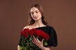 © New Africa - Smiling woman with bouquet of roses on brown background