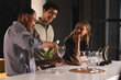 © wavebreak3 - Pouring wine, diverse colleagues enjoying conversation at modern office bar counter