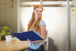 © WavebreakMediaMicro - Holding female office worker reading binder folder in modern office, with potted plant